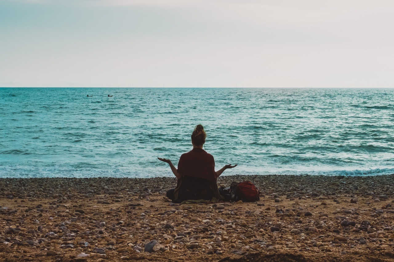 Woman facing the ocean meditating empath's holiday