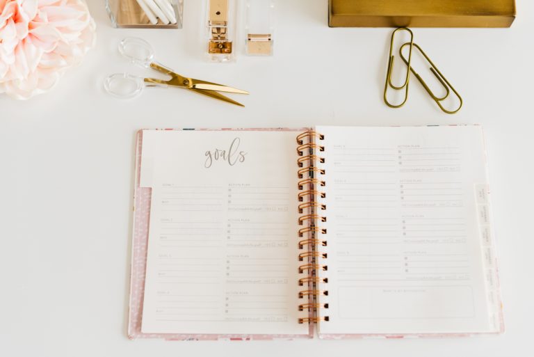 desk with office supplies and notebook with "Goals" written at the top
Create a vision board on Pinterest