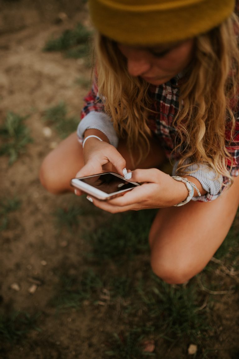 Woman sitting in grass looking at her phone.   
Create a vision board on Pinterest