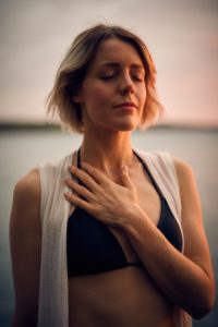 Woman with hand on chest, eyes closed looking content How to thrive as an empath
