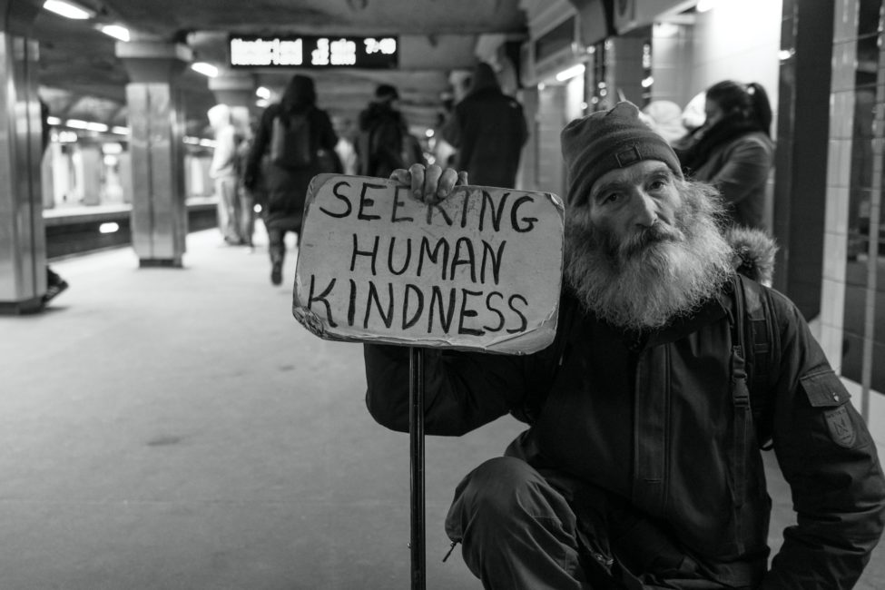 man holding sign "Seeking Human Kindness" 