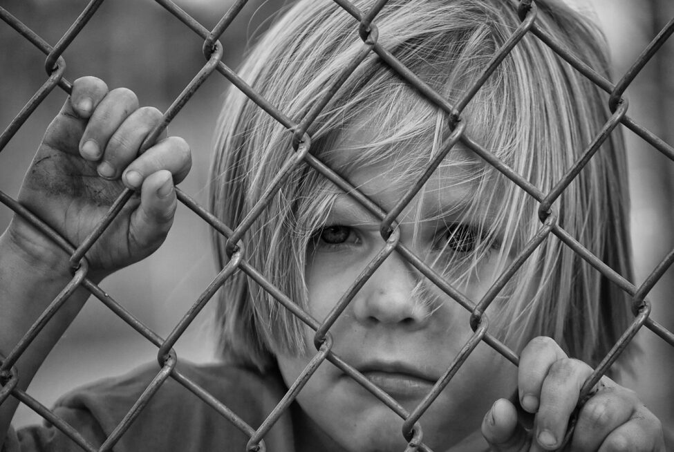 sad child looking through chain link fence limiting beliefs