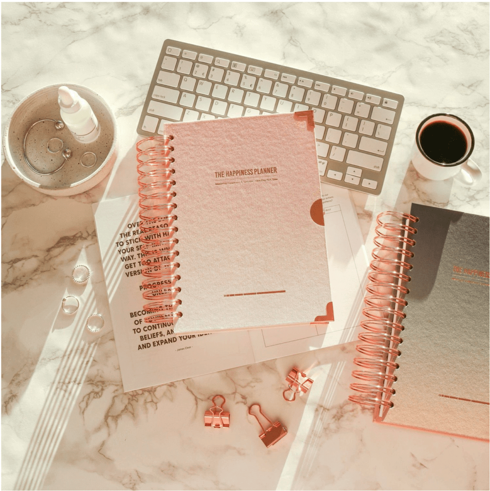 The Happiness Planner beside a keyboard and cup of coffee