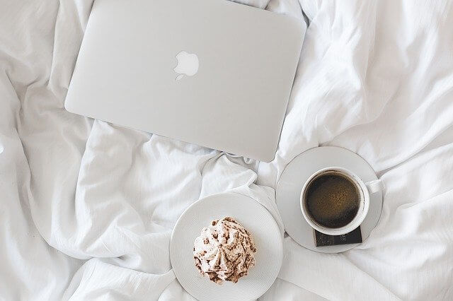 laptop, cupcake and coffee in bed