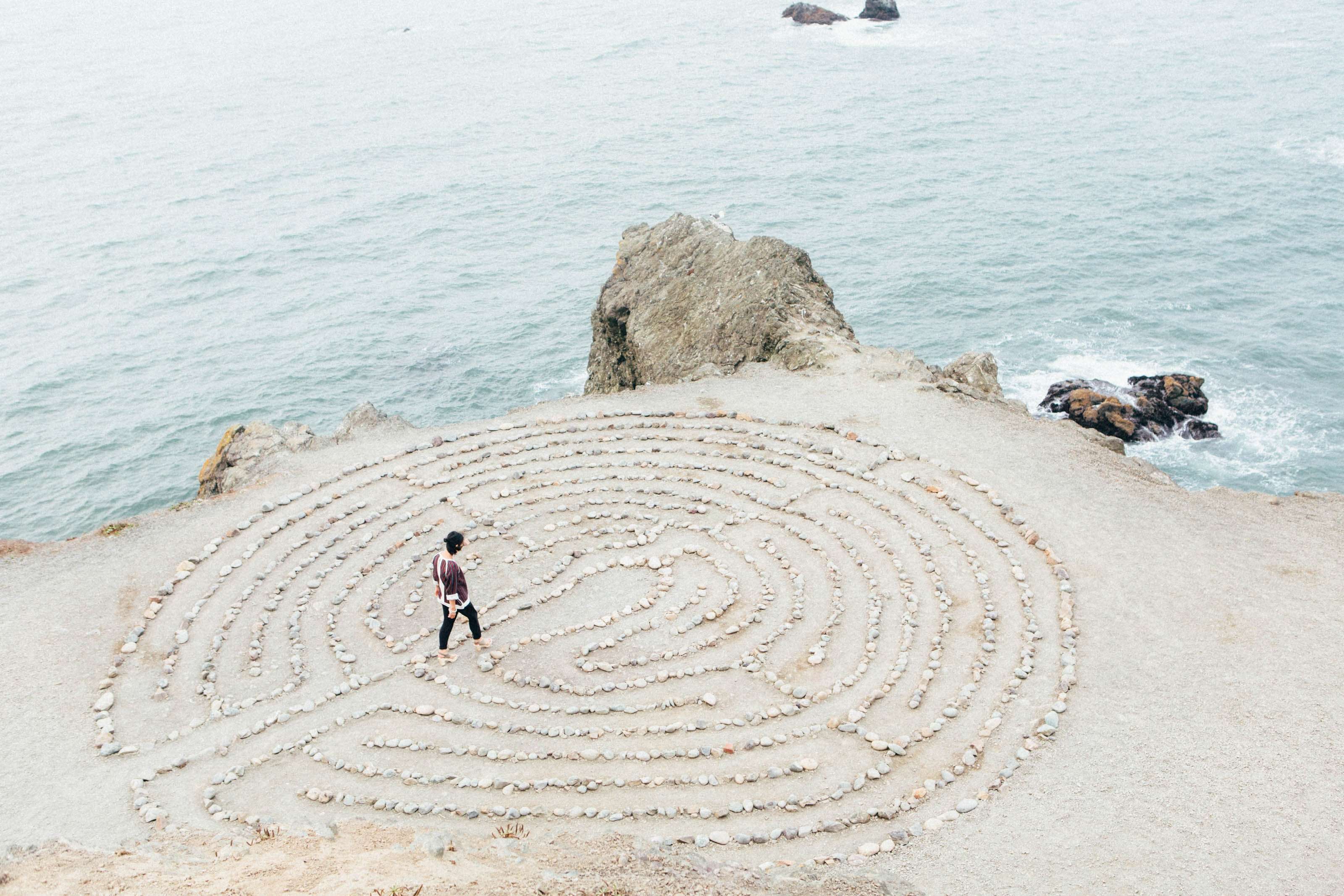 Walking in a maze drawn with rocks on the sand How to meditate