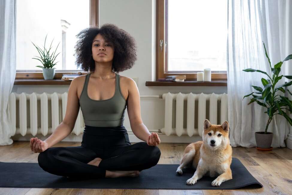 woman sitting on the floor meditating with her dog how to meditate