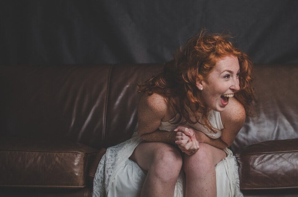 red headed woman sitting on couch laughing your true self